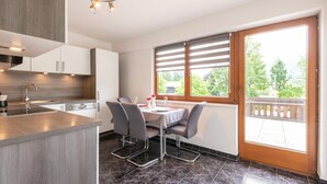Een moderne keuken met een eethoek, grote ramen en een balkon.