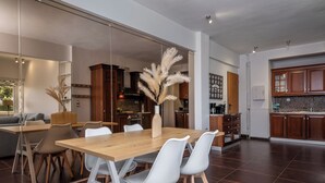 A modern kitchen with dark brown tiles, wooden cabinets, and a dining area with a wooden table and white chairs. - Relux Sea View Two Bedroom Apartment by BluPine (Athens)