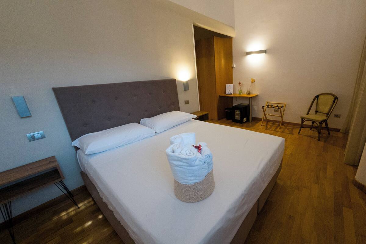 Habitación de hotel con cama, una silla, un escritorio y televisor.