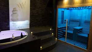 A modern spa area with a stone sculpture, a large bathtub, and a sauna. - Lungomare Suite & Spa (Naples)