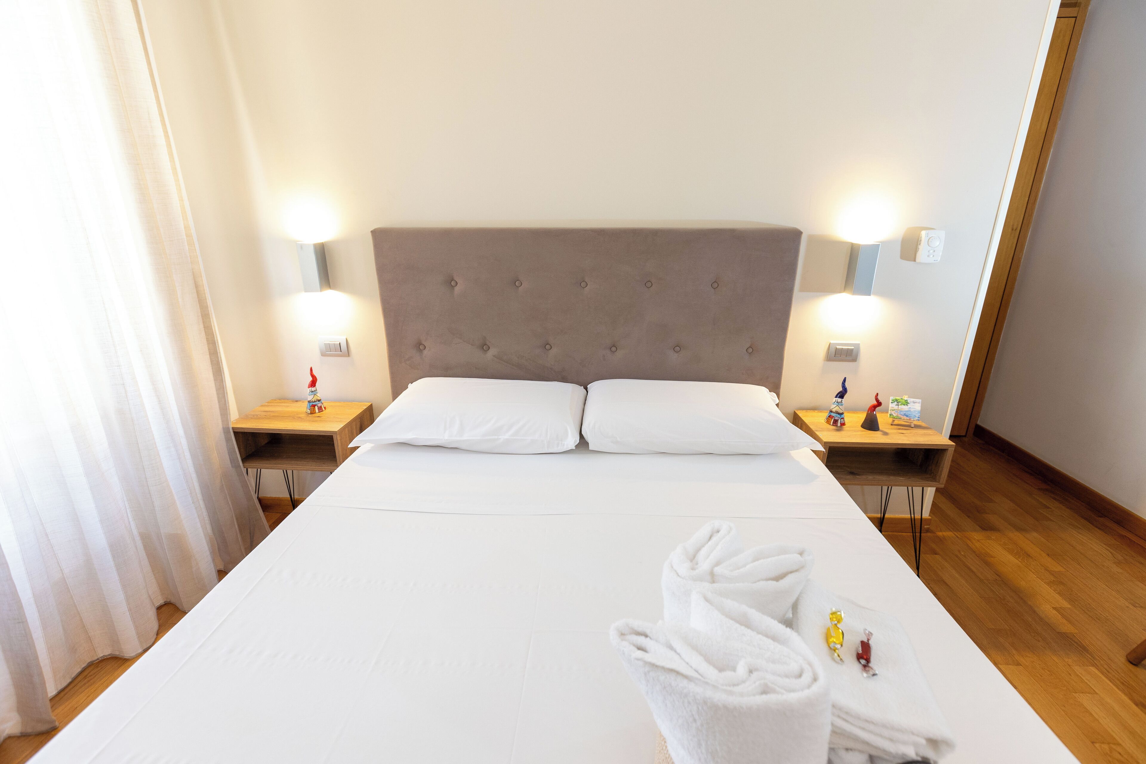 Ett hotellrum med en stor säng, två sängbord med lampor och ett trägolv.