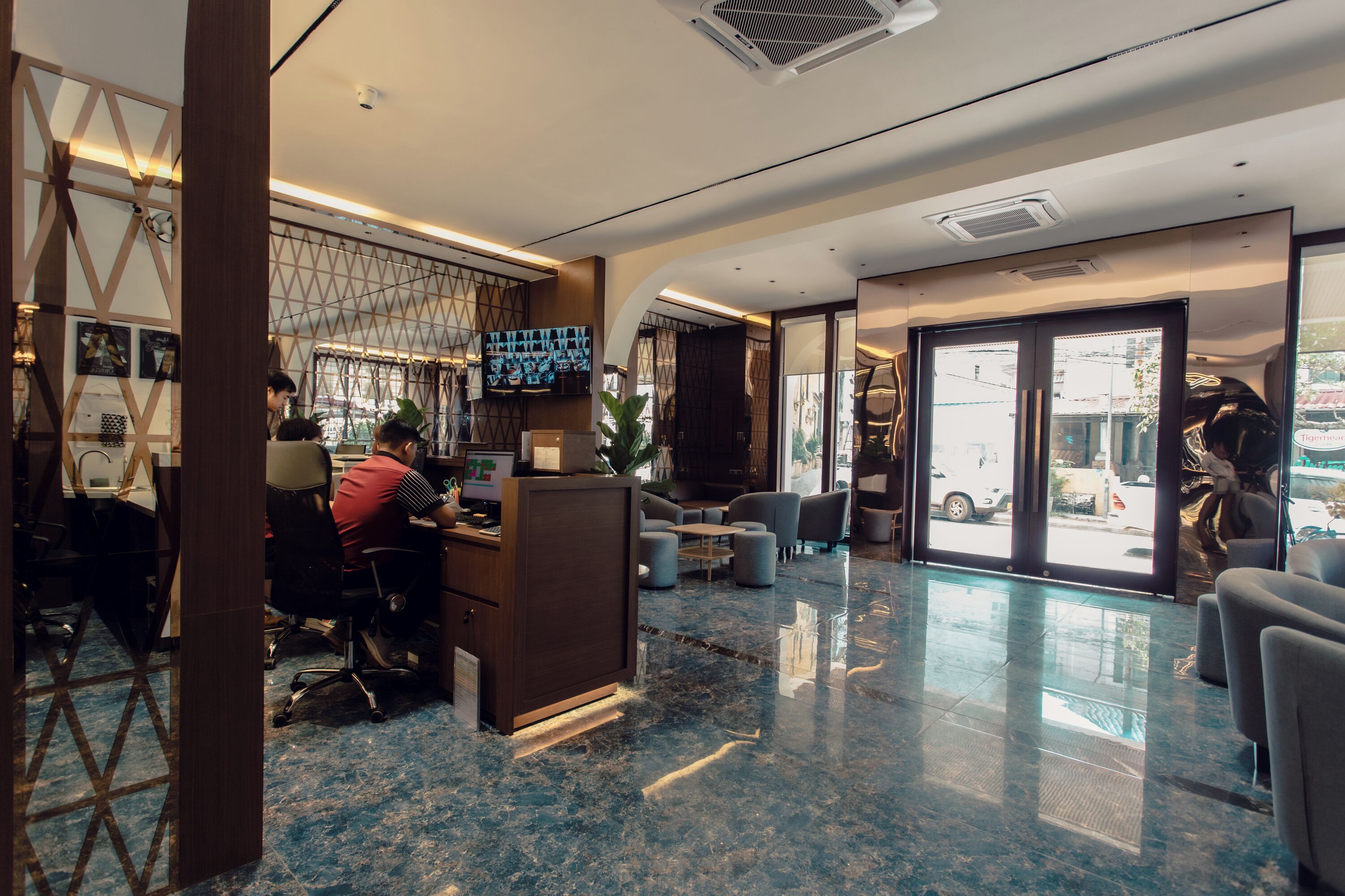A modern hotel lobby with a reception desk, seating area, and large windows offering city views.