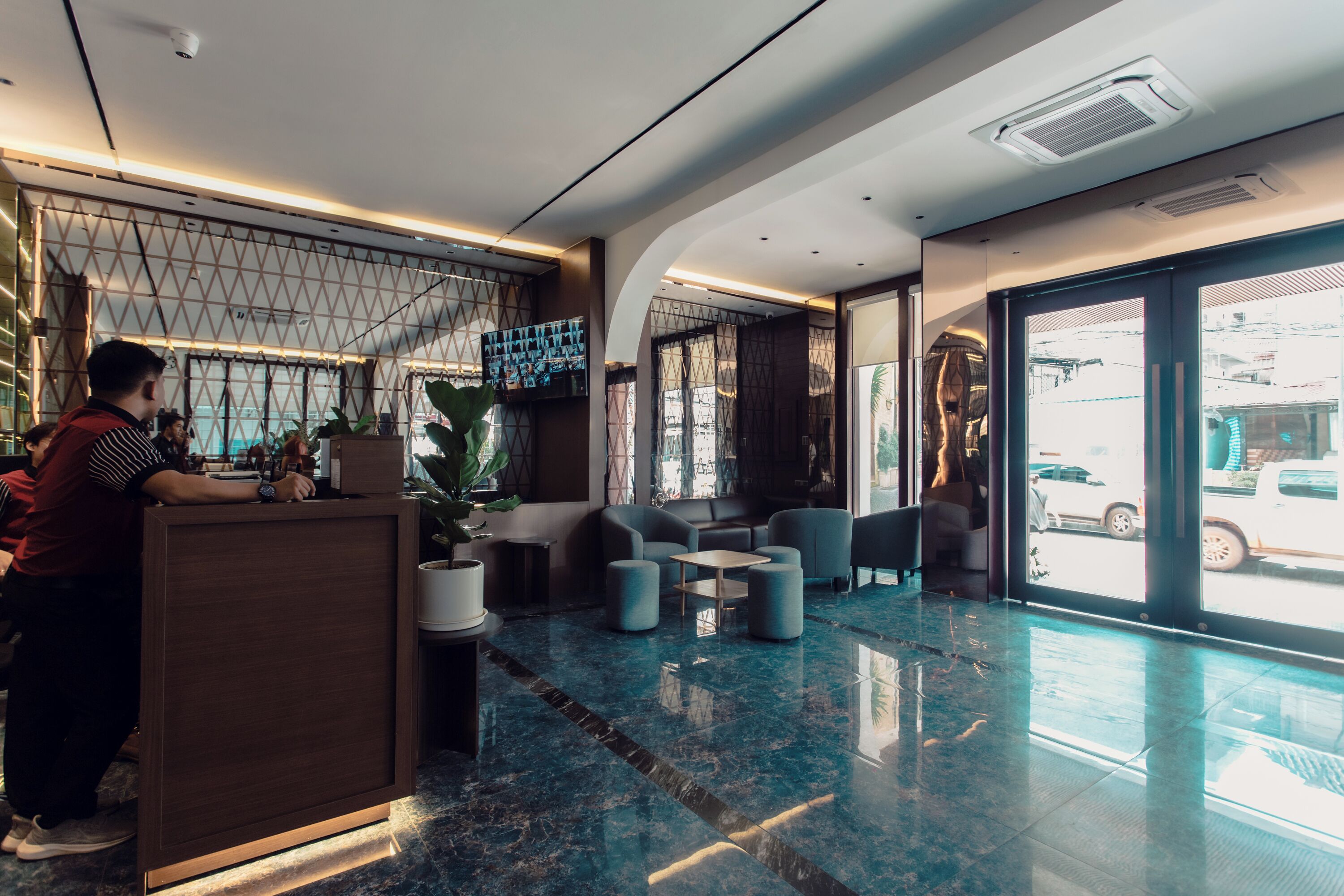 A modern lobby with a reception desk, seating area, and large windows.
