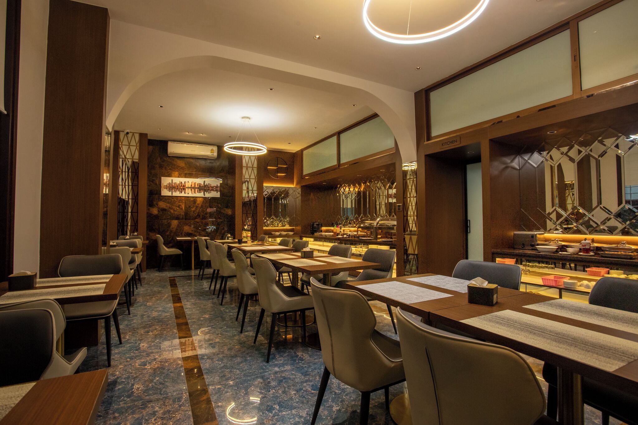 Een restaurant met een marmeren vloer, tafels met menukaarten en een zichtbare keukenruimte achter een glazen wand.