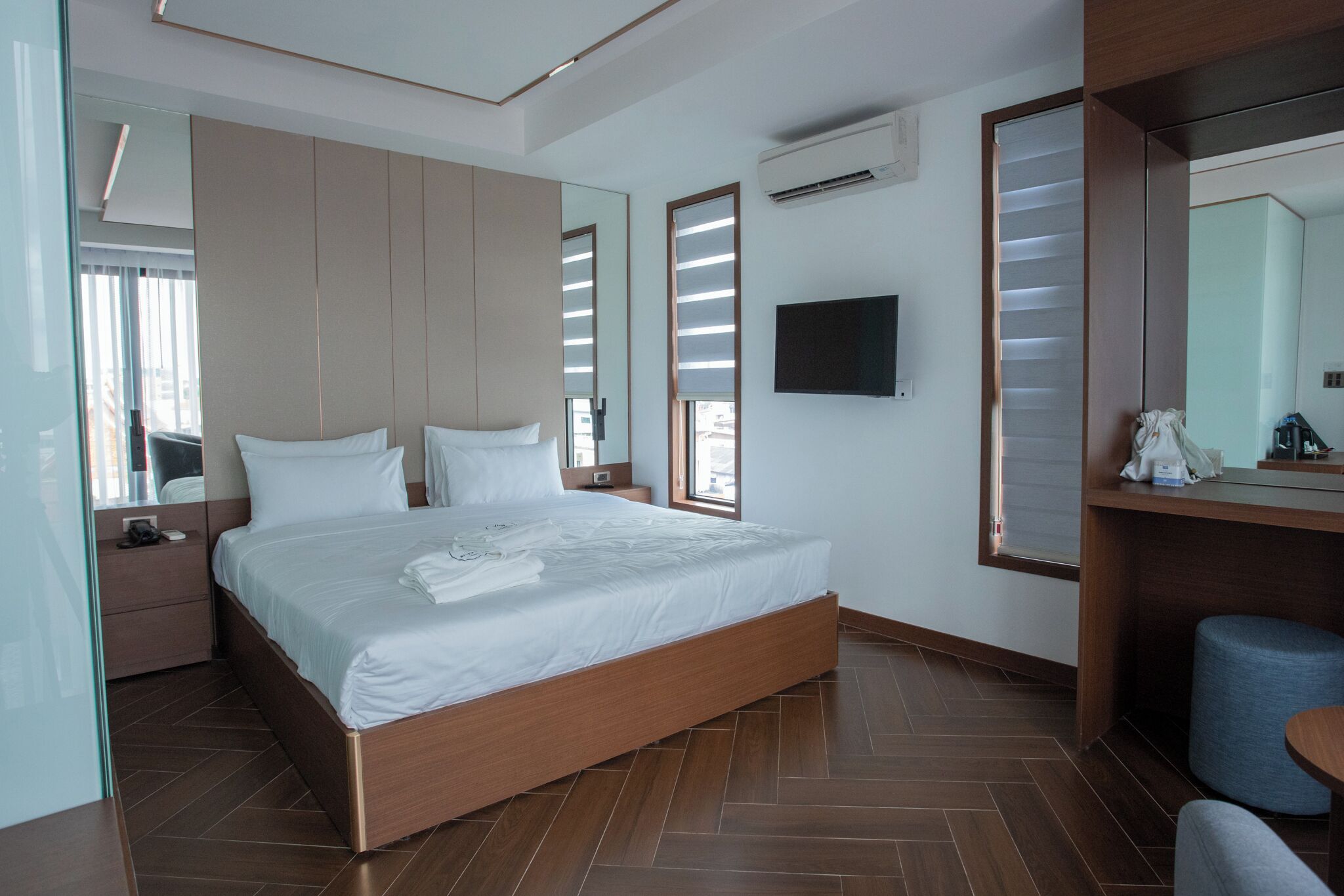 Une chambre d’hôtel moderne avec un grand lit, une télévision et un miroir.