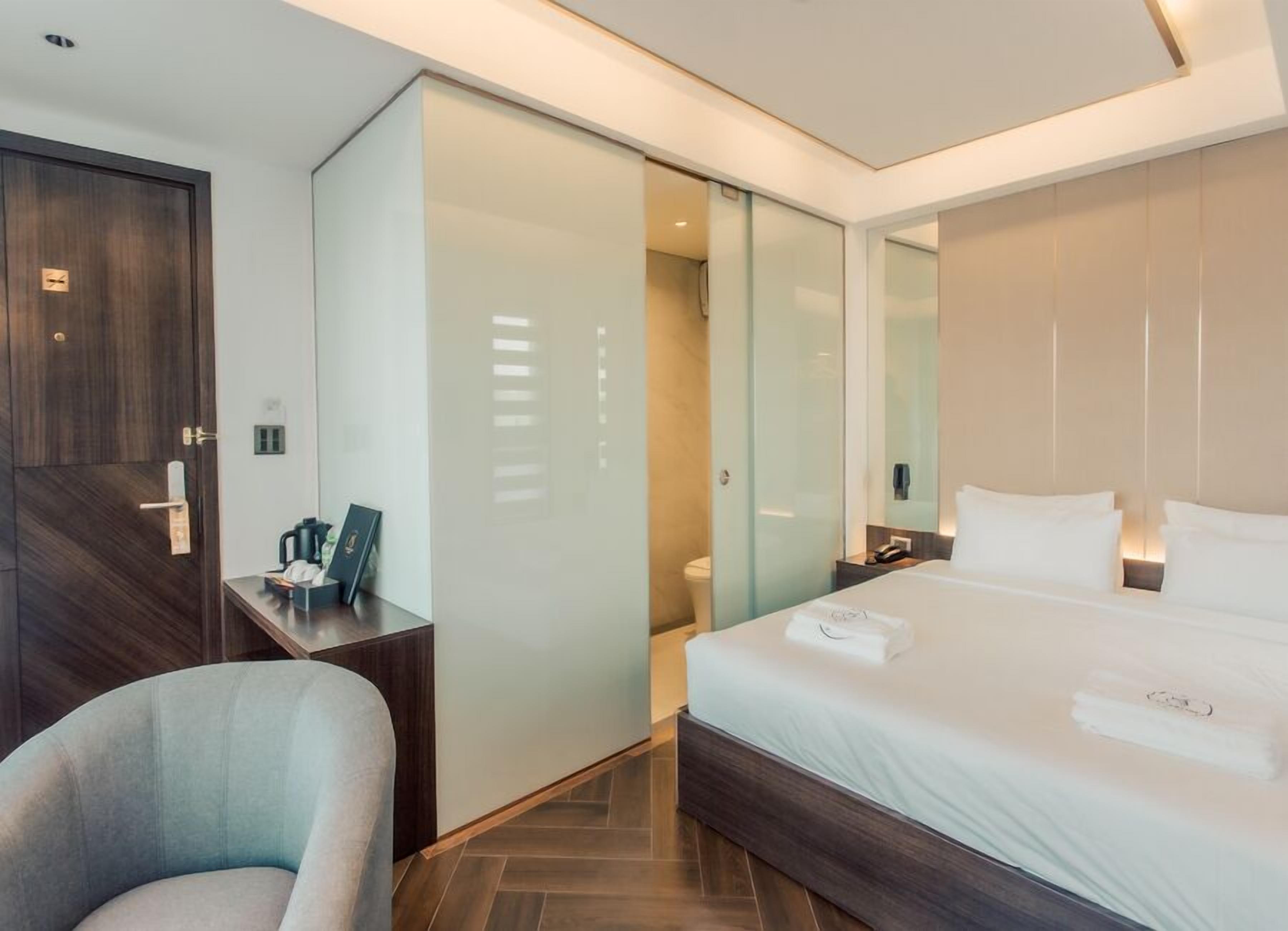 Una habitación de hotel moderna con una cama, un escritorio, una silla y un vestidor.