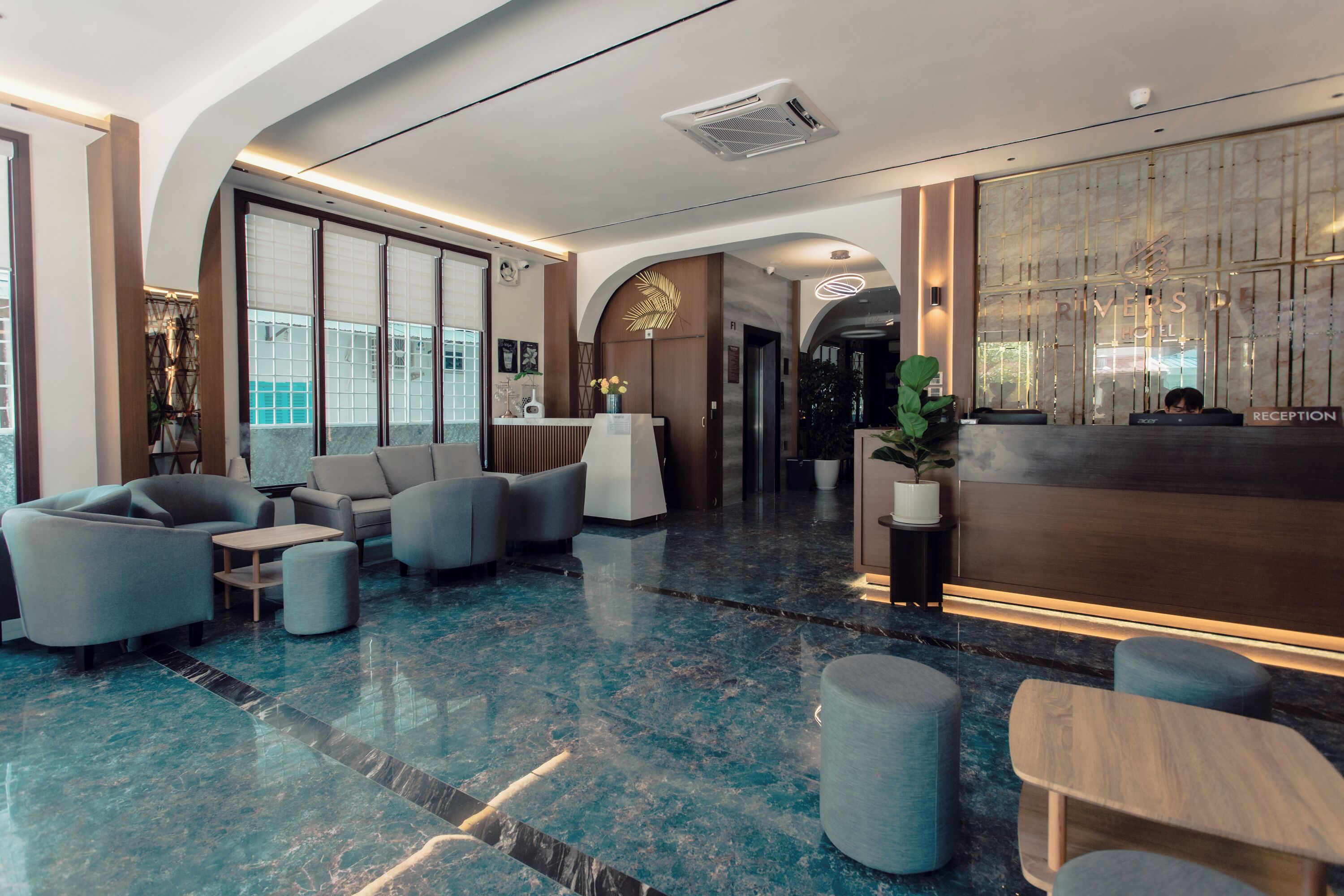A modern hotel lobby with a reception desk, seating area, and large windows.