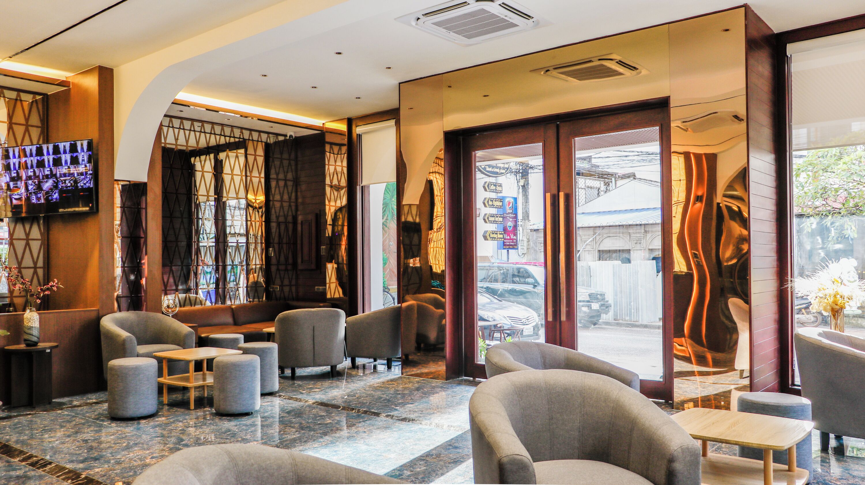 A modern interior with seating areas, a flat-screen TV, and a view of the street outside.
