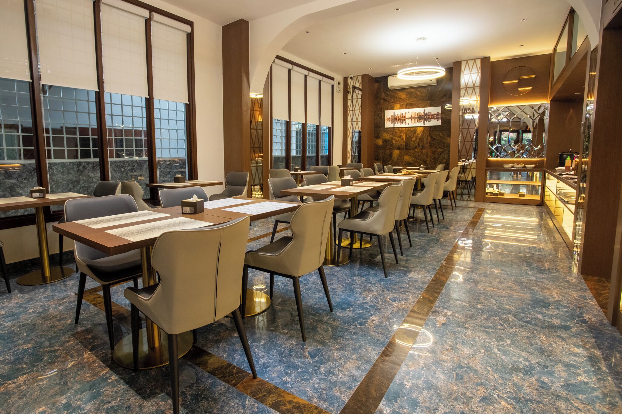 Un restaurant modern amb sòl de marbre, grans finestres i una zona de bar.