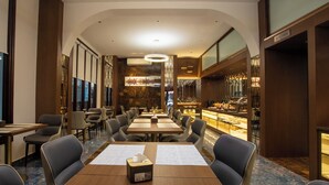 A hotel dining area with multiple tables and chairs, a kitchen area, and a bar. - Riverside Hotel (Vientiane)
