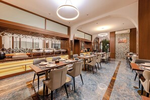 A modern dining area with a buffet, multiple tables, and chairs. - Riverside Hotel (Vientiane)