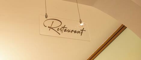A sign hanging from the ceiling with the word "Restaurant" written on it.