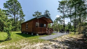 Eine Holzhütte mit Veranda, umgeben von Bäumen und einem Kiesweg.