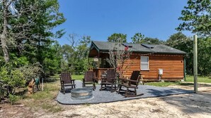 Eine rustikale Holzhütte mit einer Terrasse, Sitzgelegenheiten im Freien und einer Feuerstelle.