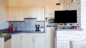 Una cocina con armarios de madera clara, microondas, cafetera y tostadora.