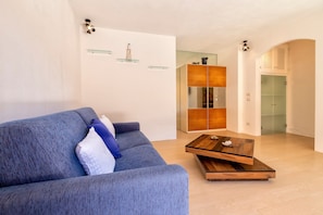A modern living room with a blue sofa, a wooden coffee table, and a glass cabinet.