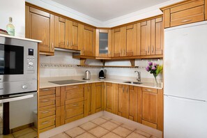 A kitchen with wooden cabinets, a stainless steel microwave, and a white refrigerator.