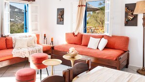 A room with a sofa, ottomans, a small table, and a bed.
