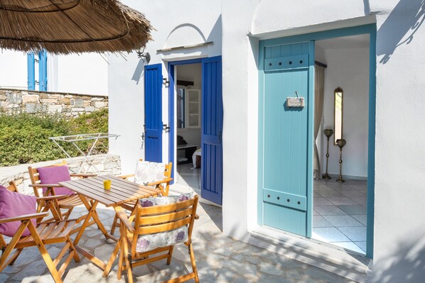 Une terrasse avec une table et des chaises, une porte bleue et un mur en pierre.