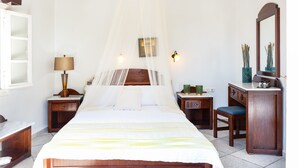 Un dormitorio con cama, mesita de noche, escritorio, silla y espejo.
