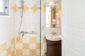 Une salle de bain avec une douche, un lavabo et un miroir.
