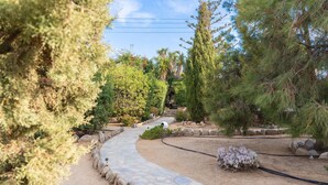 A garden pathway with a stone border, surrounded by various trees and shrubs. - Apartment In A Hotel 'Sun Rock Boutique - Villa Gerani' with Private Terrace and Air Conditioning (Naxos)