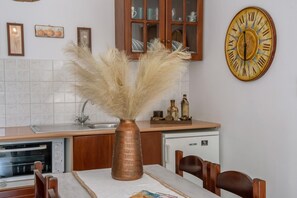 Une cuisine avec un vase en cuivre, une horloge et une table à manger.