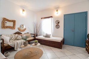 Une pièce avec un canapé, un lit, une porte bleue et un miroir au mur.