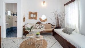 A living room with a sofa, a coffee table, a mirror, and a window with curtains. - Apartment In A Hotel 'Sun Rock Boutique - Villa Gerani' with Private Terrace and Air Conditioning (Naxos)