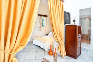 Une chambre à coucher avec un lit, des rideaux, une commode et une petite fenêtre.