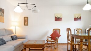 Un salon comprenant un canapé, une table basse en bois, un fauteuil à bascule et une table à manger avec des chaises.
