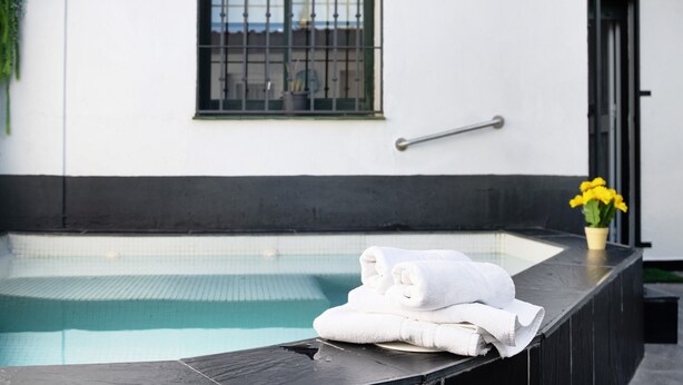 Un espace piscine avec une pile de serviettes, une fenêtre grillagée et une plante en pot.