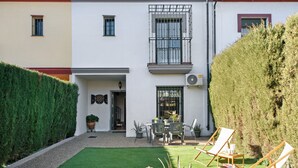 Un bâtiment à deux étages doté d’un balcon, d’une petite terrasse avec des chaises et d’un arbuste taillé avec soin.