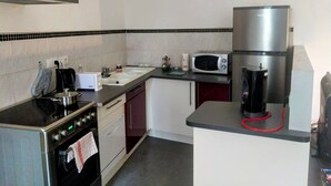 Una cocina compacta con estufa, microondas y refrigerador.