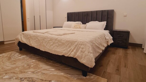 A bedroom with a bed, nightstands, a wardrobe, and a patterned rug. - Luxury Modern 3bdr with a pool and  gym (Nairobi)