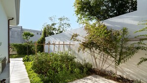 Un jardin agrémenté d’une treille en bois, d’un chemin dallé et d’un mur blanc.