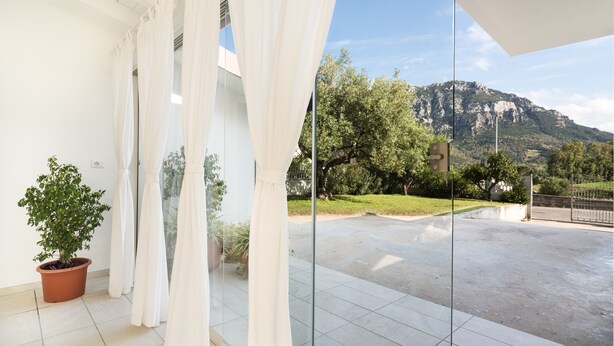 Un balcon avec vue sur les montagnes, des rideaux blancs et des plantes en pot.