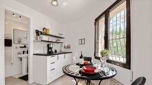 Een moderne keuken met witte kasten, een zwart-wit betegelde tafel en een raam met uitzicht op groen.