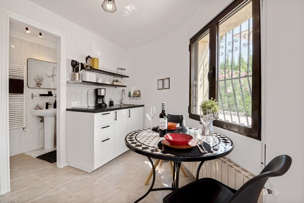 A modern kitchen with white cabinetry, a black and white tiled table, and a window with a view of greenery.