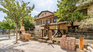 A rustic stone building with a wooden balcony, surrounded by trees.