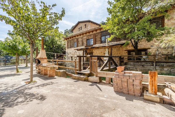 A rustic stone building with a wooden balcony, surrounded by trees.