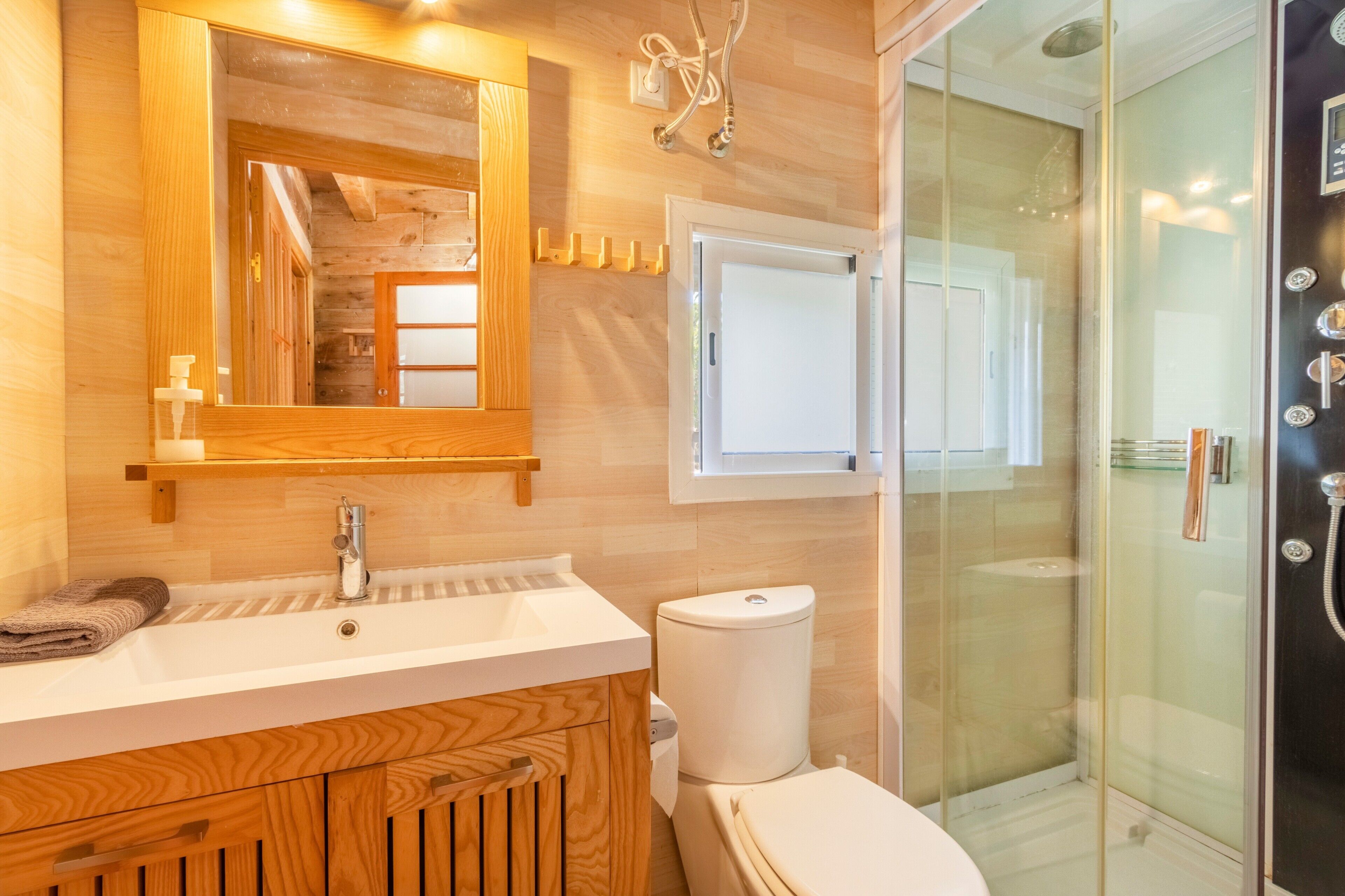 A modern bathroom with a wooden vanity, a glass shower enclosure, and a white toilet.