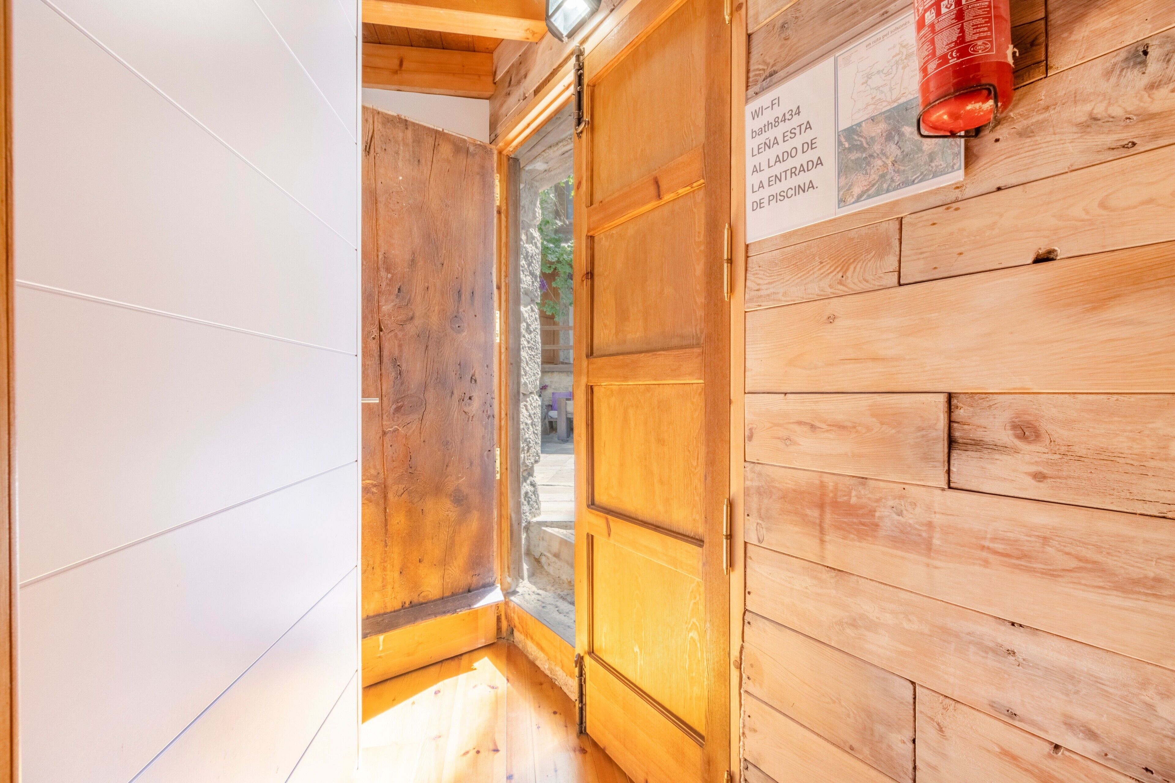 Interior de madera con una puerta de madera, un extintor y un cartel con texto.