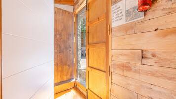Interior de madera con una puerta de madera, un extintor y un cartel con texto.