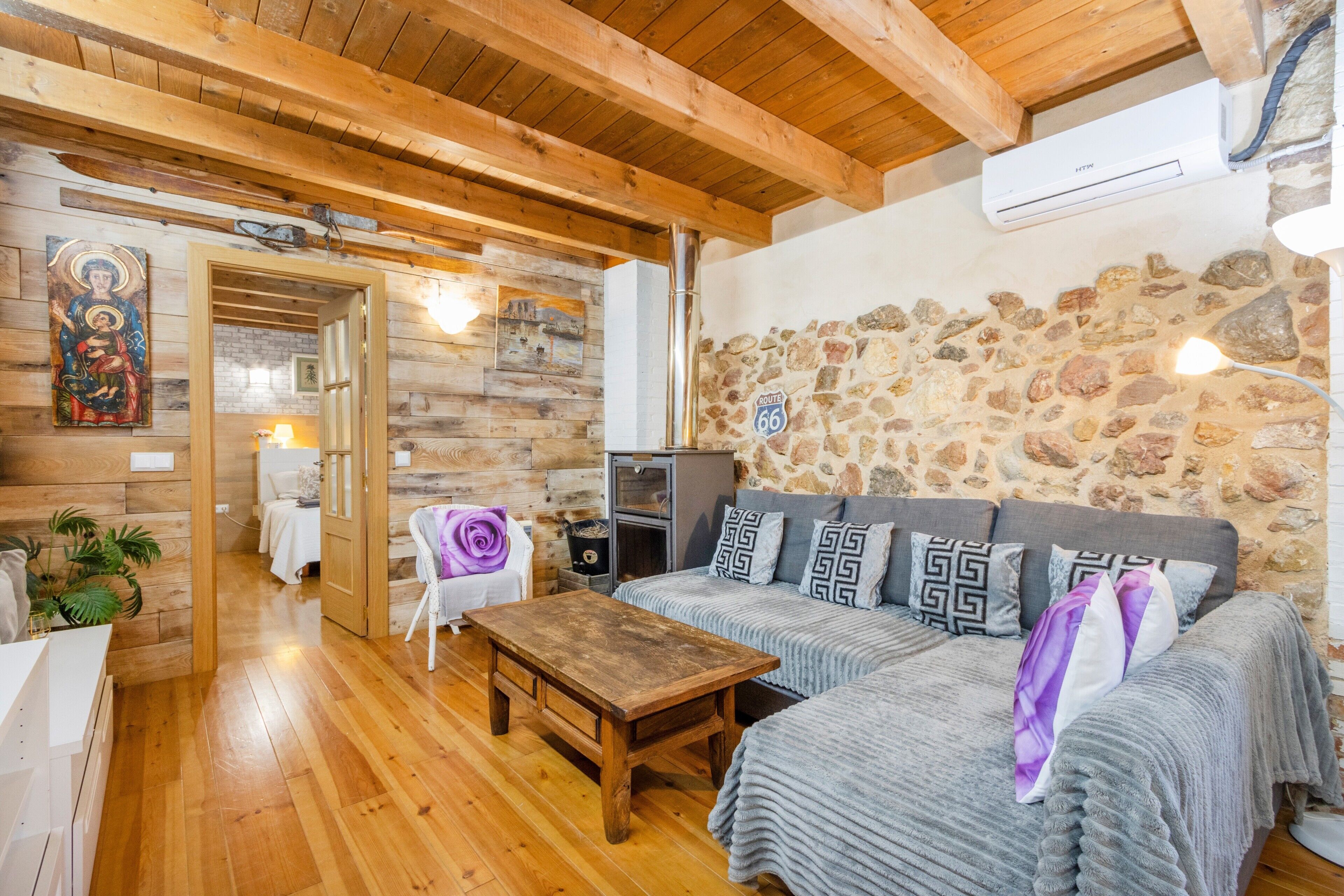 Una habitación acogedora con suelos de madera, una pared de piedra, un sofá, una mesa y un televisor.