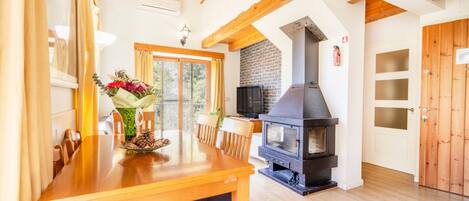 Un comedor con una mesa y sillas de madera, una chimenea y un televisor.