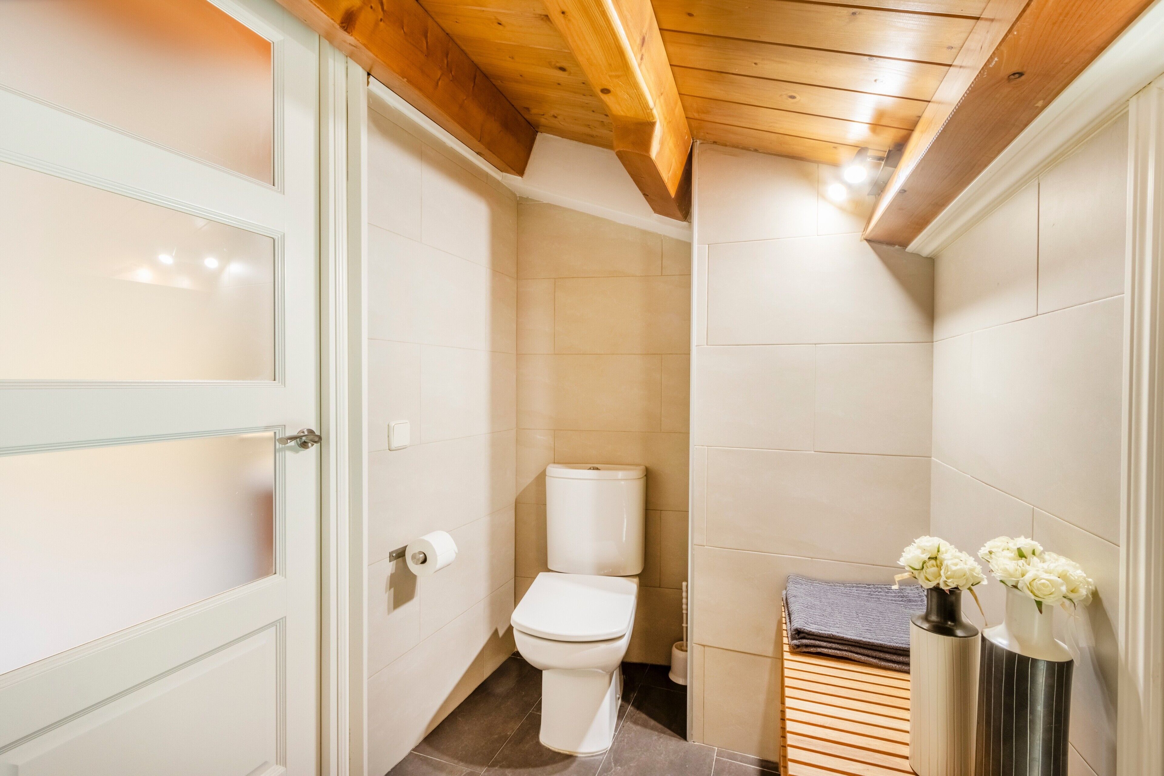 Een badkamer met een toilet, een handdoekhouder en een vaas met bloemen.