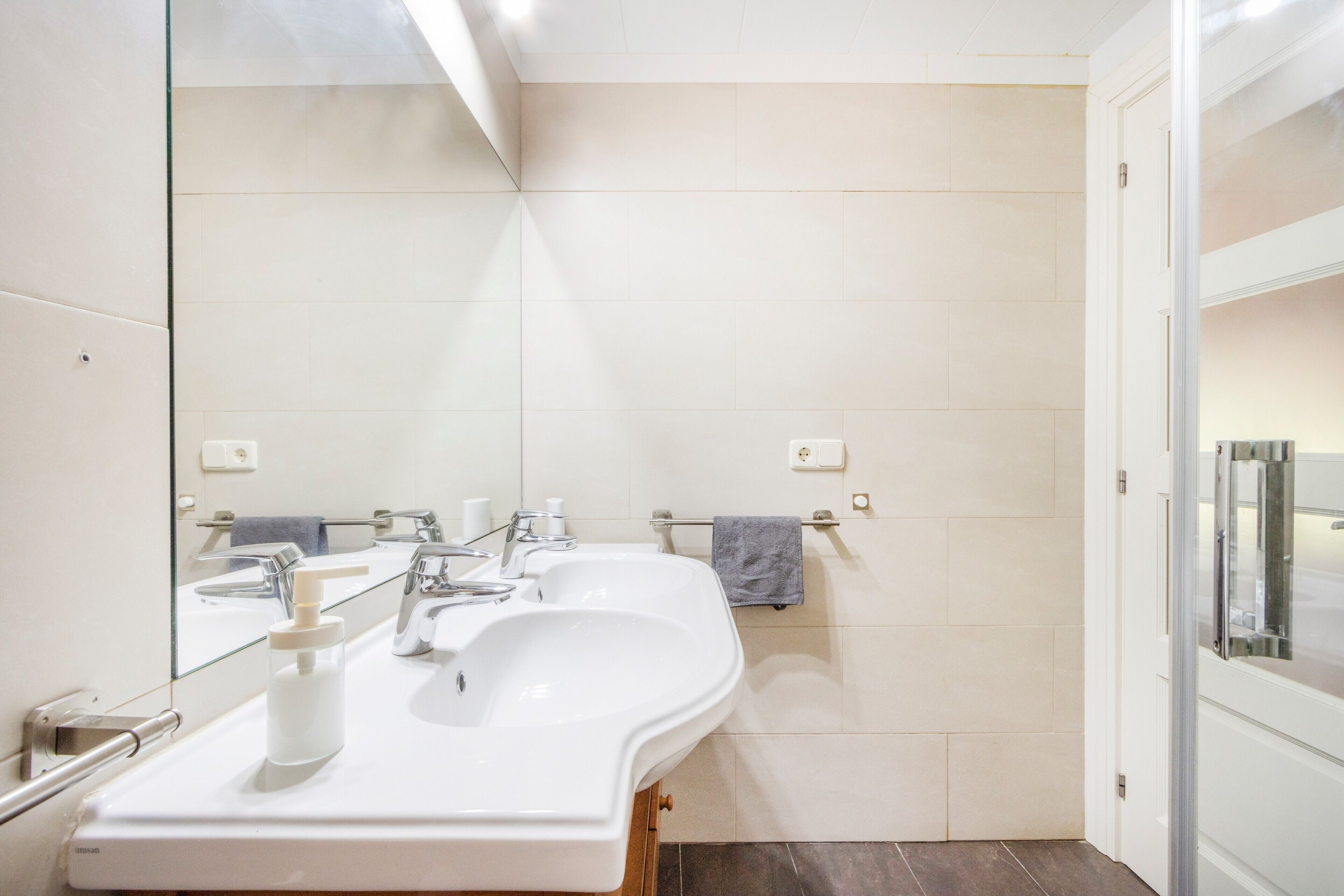 Un baño moderno con dos lavamanos, un espejo grande y un perchero para toallas.