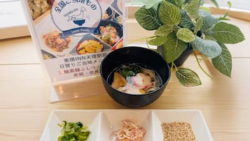 Um menu com diversos pratos, uma tigela de sopa e uma planta sobre a mesa.