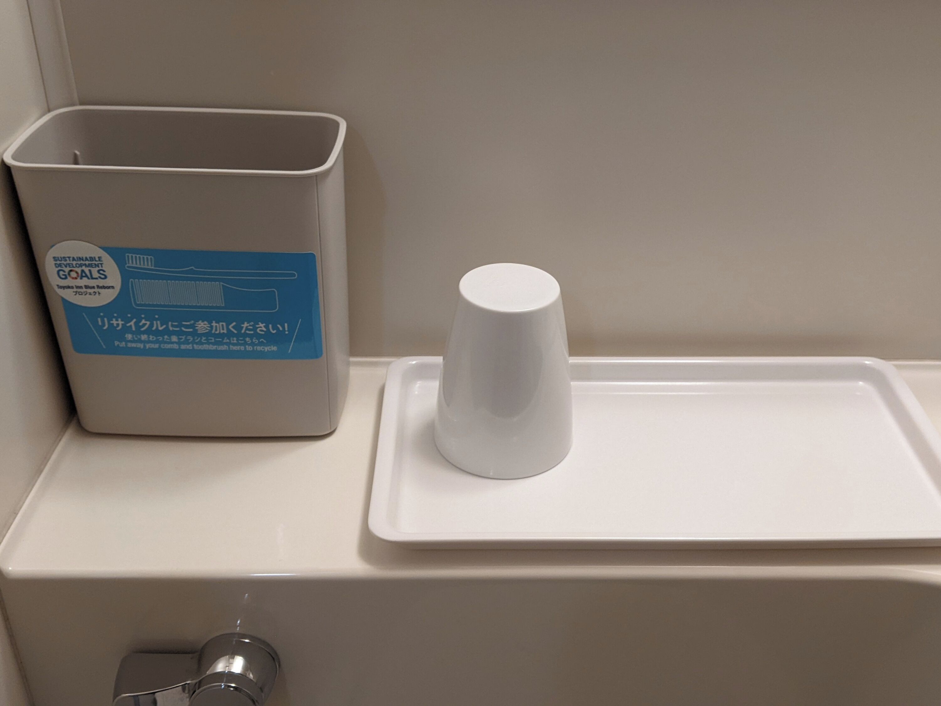 A bathroom sink with a trash bin and a cup holder.